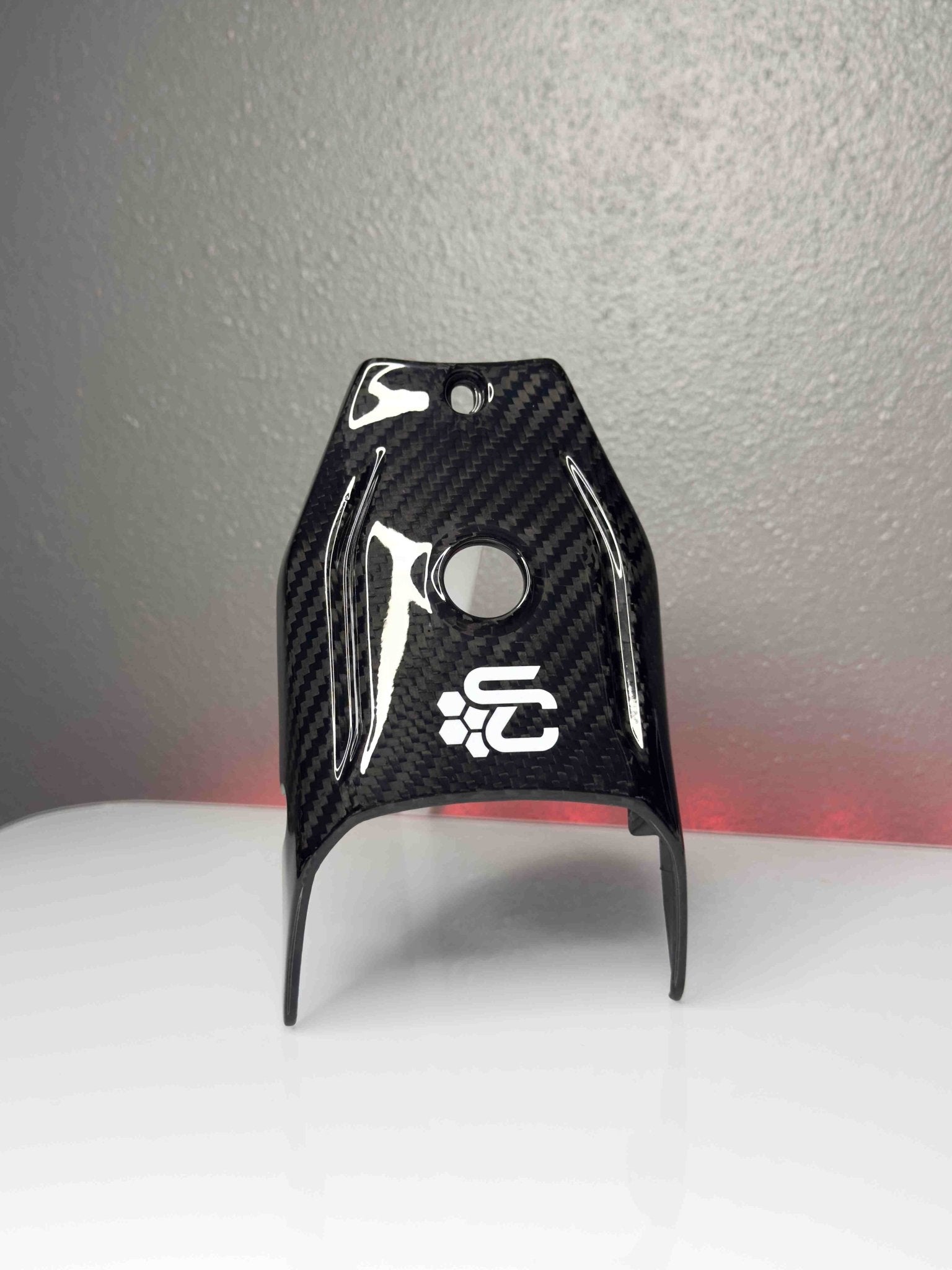 Carbon fiber part with a logo on a gray background