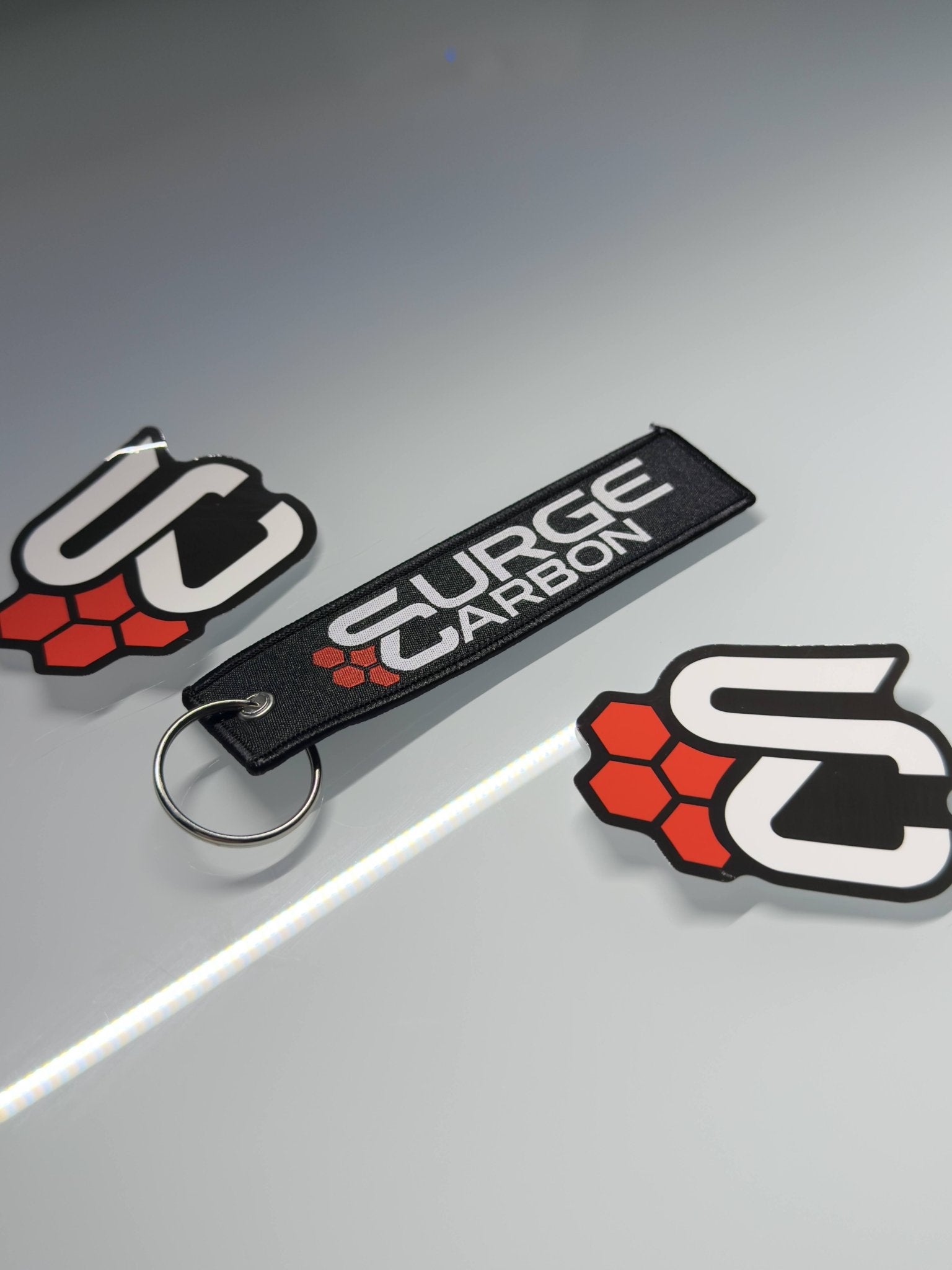 Surge Carbon keychain and logo on a gray background